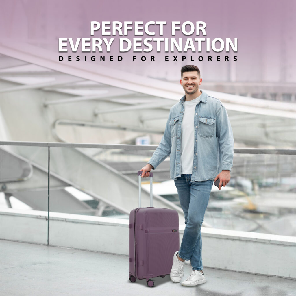 Smiling man at airport with American Traveller purple hard luggage trolley bag, featuring telescopic handle and smooth wheels